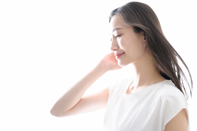 目を閉じて髪をかき上げる女性