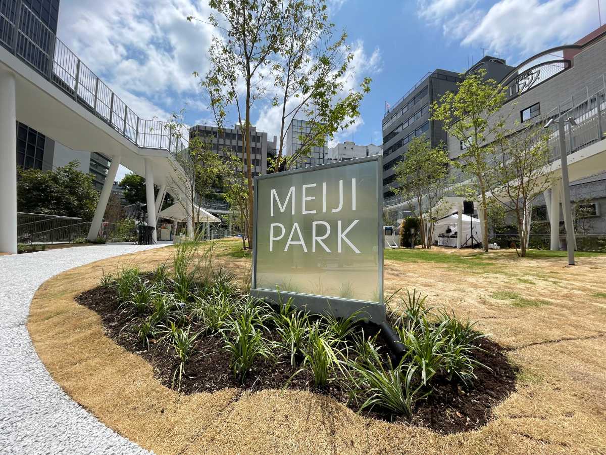 明治公園のMEIJI PARK看板と芝生広場、背景の立体園路